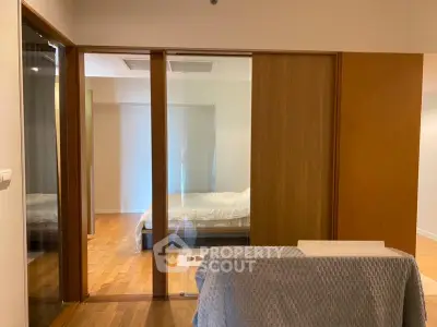 Spacious bedroom with wooden flooring and sliding glass doors in modern apartment.