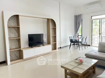 Spacious modern living room with sleek TV unit and dining area, featuring large windows and elegant decor.