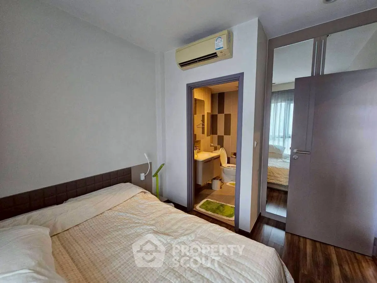 Cozy bedroom with ensuite bathroom and mirrored closet in modern apartment.