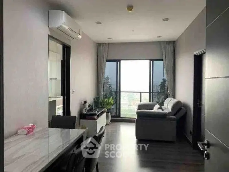 Modern living room with large windows and stylish furniture offering a stunning city view.