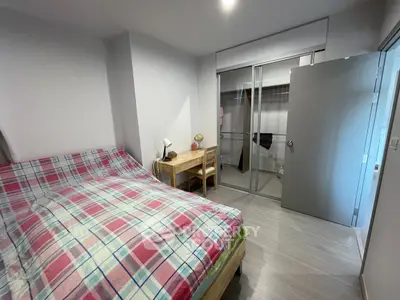 Cozy bedroom with plaid bedding and a small study desk, featuring a sliding door closet.
