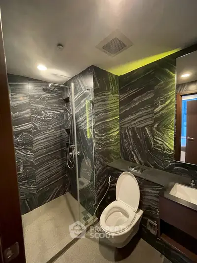 Luxurious modern bathroom with sleek marble walls and glass shower enclosure.