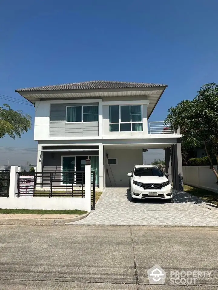 Modern two-story house with driveway and car parked, featuring sleek design and spacious exterior.