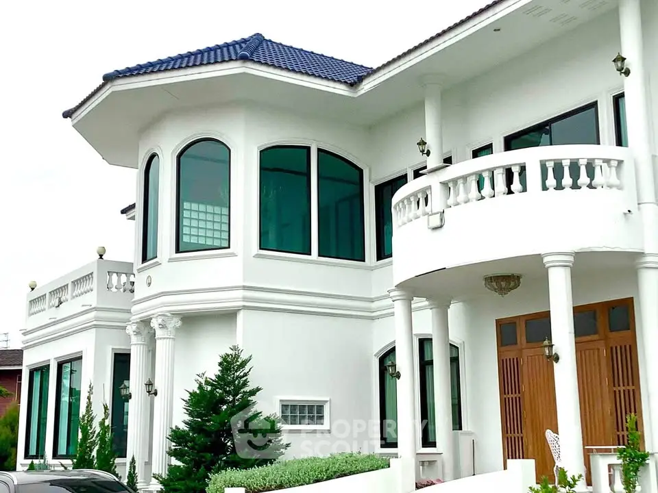 Stunning white villa with blue roof and elegant balcony, showcasing luxury architecture.