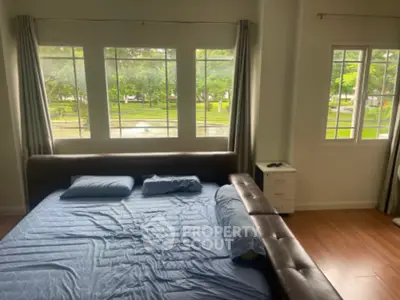 Spacious bedroom with large windows offering serene garden views and natural light.