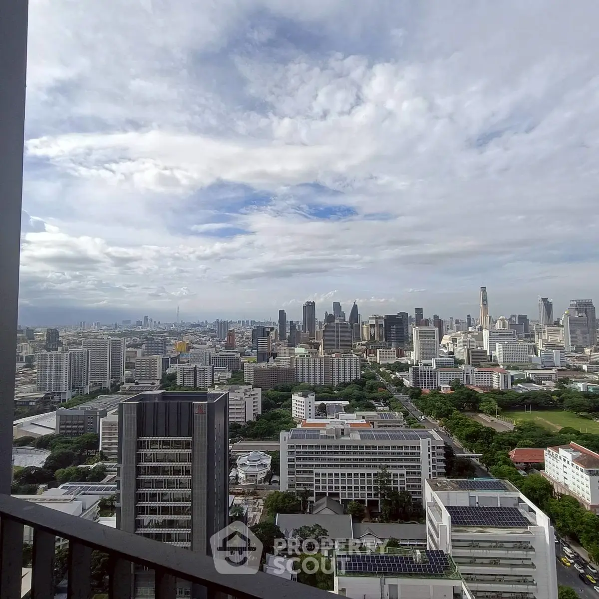 Stunning cityscape view from a high-rise balcony showcasing urban skyline and lush greenery.