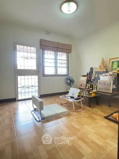 Cozy living room with natural light, tiled floor, and minimalist decor, perfect for relaxation and meditation.