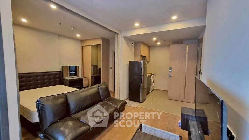 Modern studio apartment with open layout and sleek furnishings, featuring a compact kitchen and cozy living area.