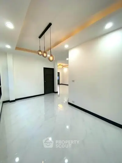 Spacious modern living room with elegant lighting and glossy white flooring.