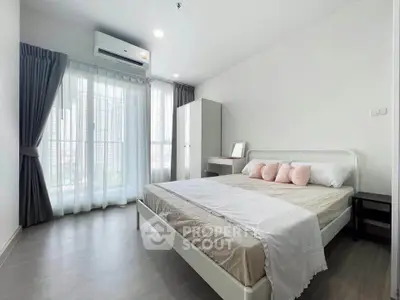 Spacious modern bedroom with large windows and stylish decor in a high-rise apartment.