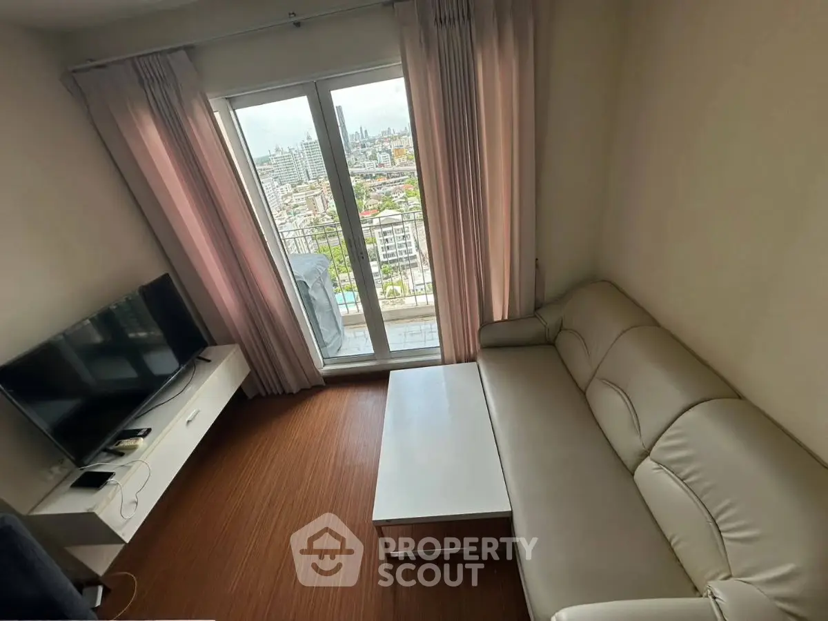 Cozy living room with city view, featuring a sleek sofa and modern TV setup, perfect for urban living.
