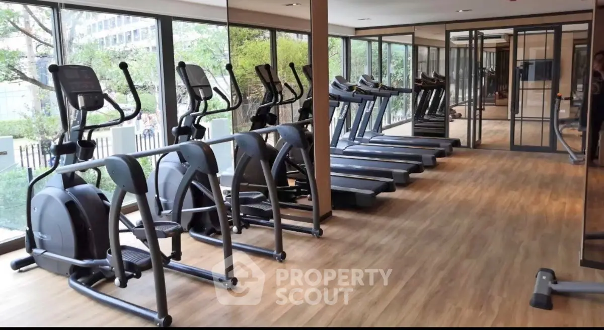 Modern gym with cardio equipment and large windows in a residential building.