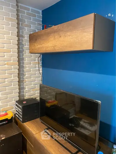 Modern living room with stylish TV setup and brick accent wall.