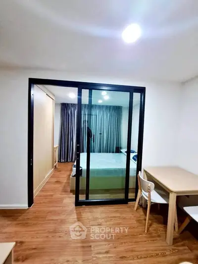 Modern bedroom with sliding glass doors and wooden flooring, featuring a cozy study area.