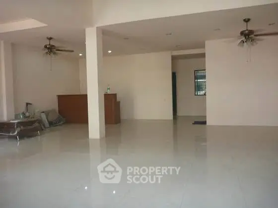 Spacious open-plan living area with ceiling fans and tiled flooring.
