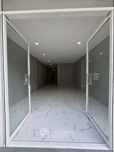 Spacious commercial space with elegant marble flooring and glass doors, perfect for retail or office use.