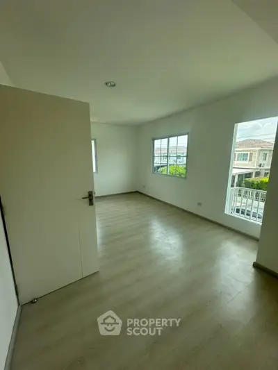 Spacious empty room with large windows and wooden flooring, ideal for customization.
