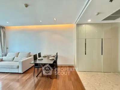 Modern living room with dining area and sleek cabinetry, featuring elegant lighting and wooden flooring.