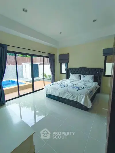 Spacious bedroom with pool view and elegant decor in modern home