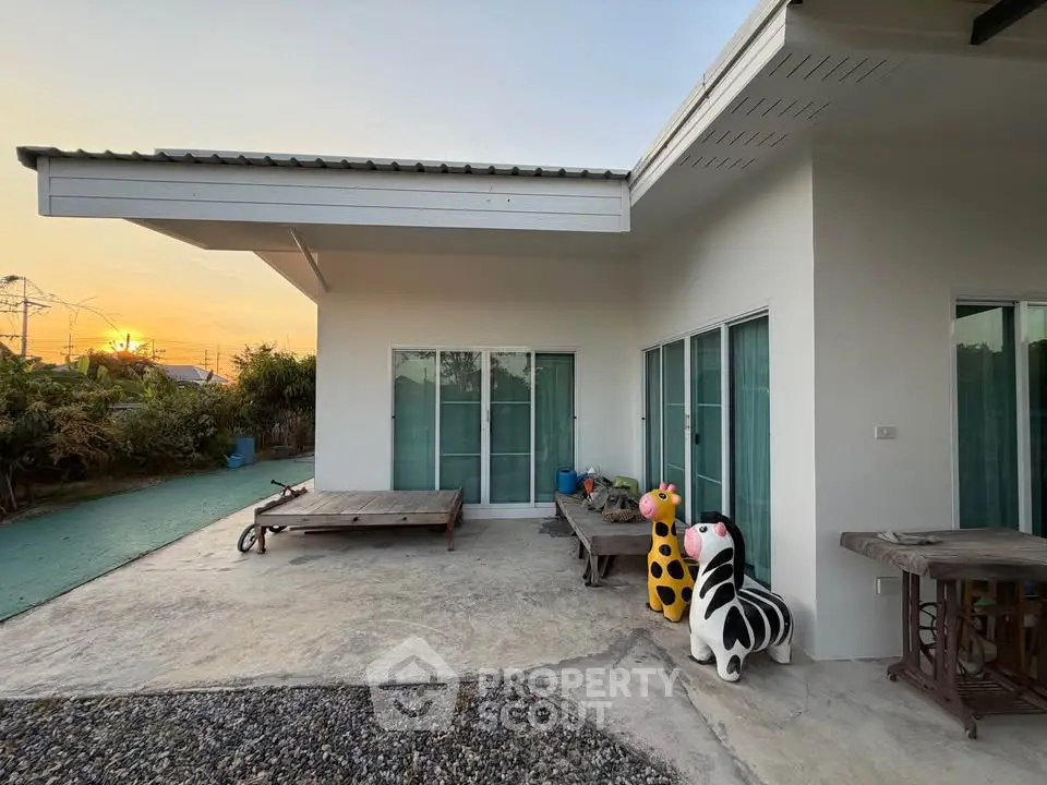 Charming modern home exterior with spacious patio and unique decor at sunset.