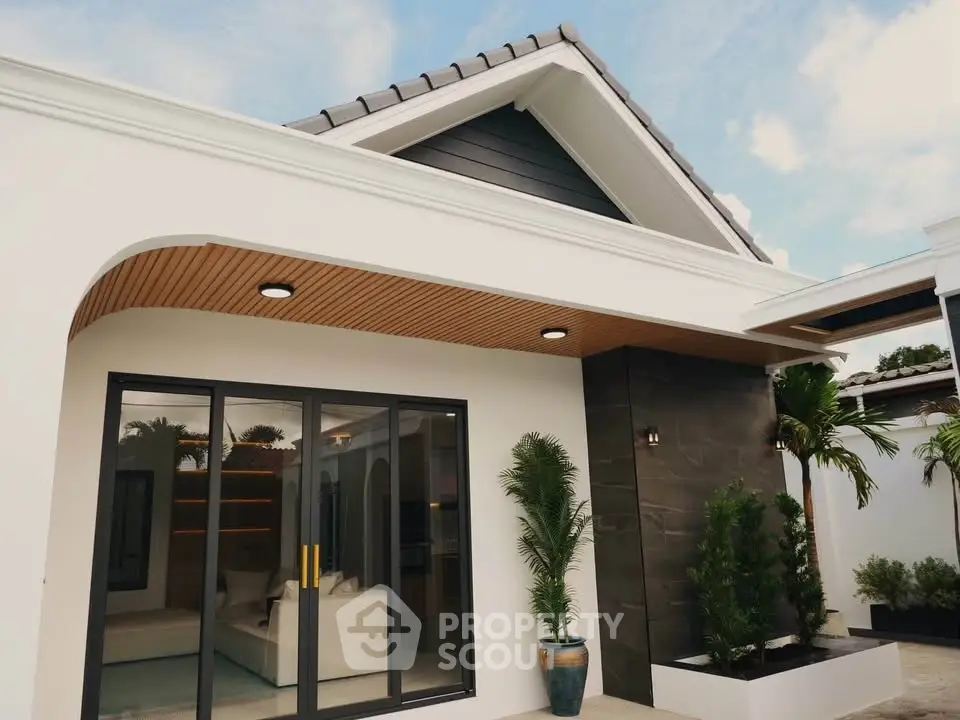 Modern single-story house with sleek design and large glass doors, featuring a stylish exterior and lush greenery.