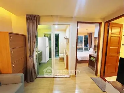Cozy apartment interior with wooden flooring, sliding glass doors, and a glimpse of a bedroom and kitchen.