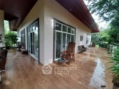 Spacious wooden deck with sliding glass doors and lush greenery, perfect for outdoor relaxation.