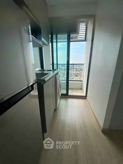 Modern kitchen with balcony view, featuring sleek appliances and bright natural light.