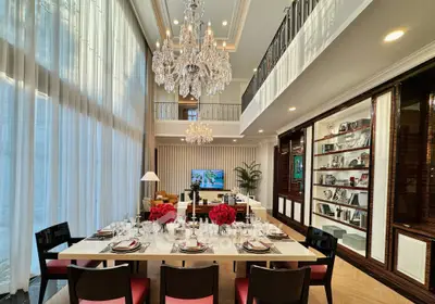 Luxurious dining and living area with high ceilings and elegant chandeliers.
