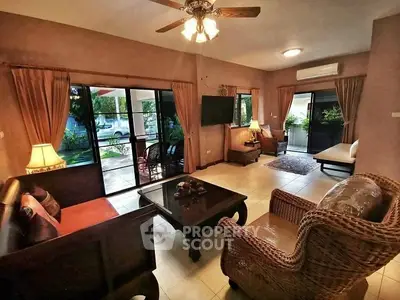 Spacious living room with elegant decor and garden view, featuring wicker furniture and ceiling fan.