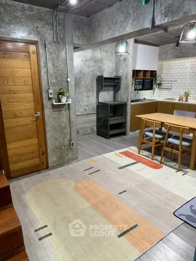 Stylish modern kitchen with open layout and dining area, featuring sleek concrete walls and wooden accents.