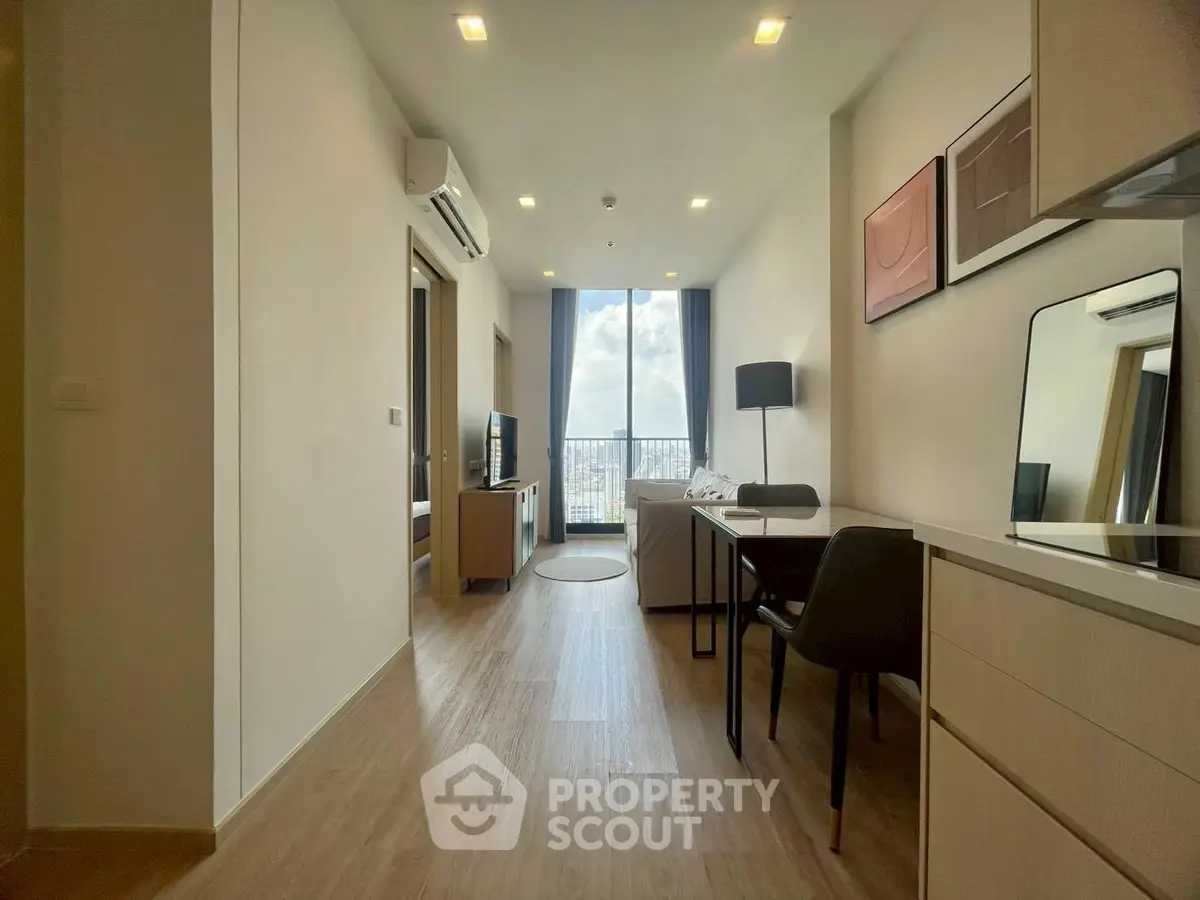 Modern living room with open layout and city view from balcony, featuring stylish decor and natural light.