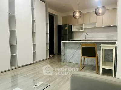 Modern kitchen with sleek cabinetry and marble island in open layout apartment.