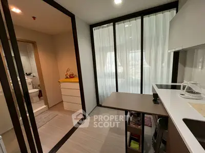 Modern apartment interior with compact kitchen and bathroom, featuring sleek design and natural light.