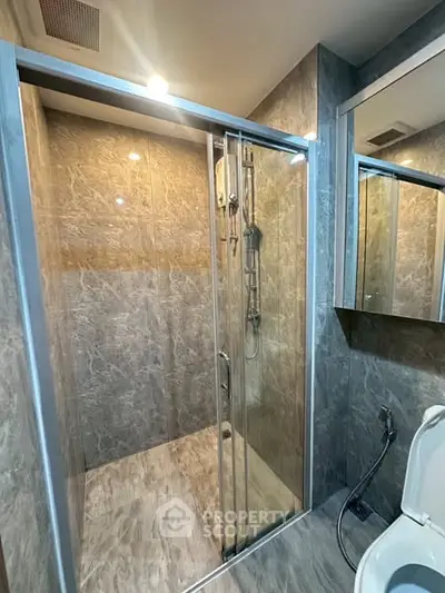 Modern bathroom with glass shower enclosure and marble walls