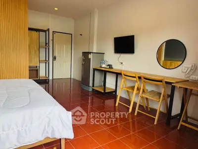 Charming studio apartment with modern furnishings and vibrant red tile flooring.