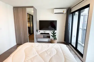 Modern bedroom with large window, wall-mounted TV, and sleek wardrobe design.