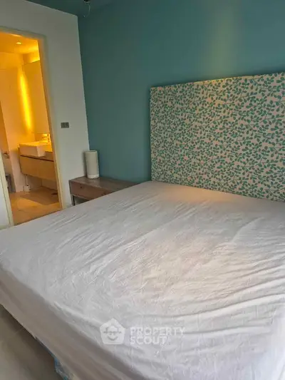 Cozy bedroom with ensuite bathroom and stylish headboard in modern apartment.