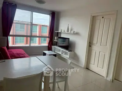 Modern living room with sleek furniture and large window offering natural light.