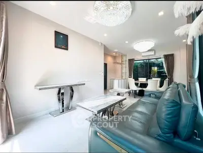 Luxurious living room with elegant furniture and modern decor, featuring a stunning chandelier and large windows.