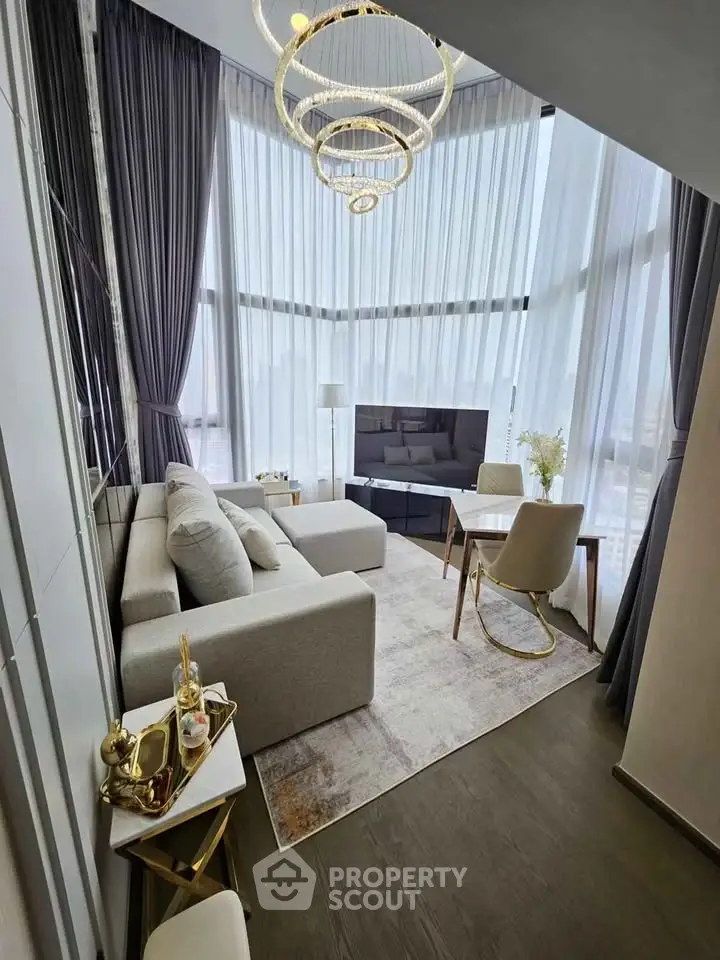 Luxurious living room with high ceilings, modern chandelier, and floor-to-ceiling windows offering stunning views.