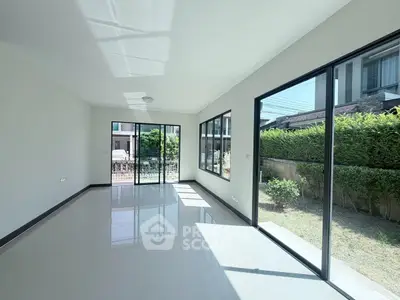 Spacious sunlit living room with large windows and garden view in modern home