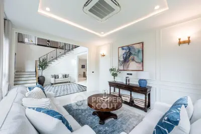 Luxurious living room with elegant decor and staircase, featuring plush seating and modern art.