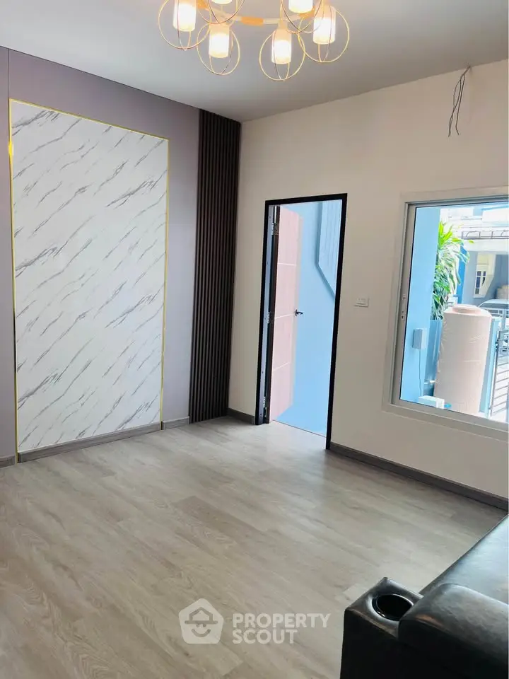 Modern living room with elegant flooring and stylish lighting, featuring a large window and chic wall design.