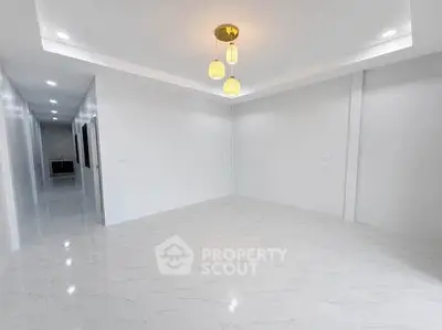 Spacious empty living room with modern lighting and glossy white flooring.