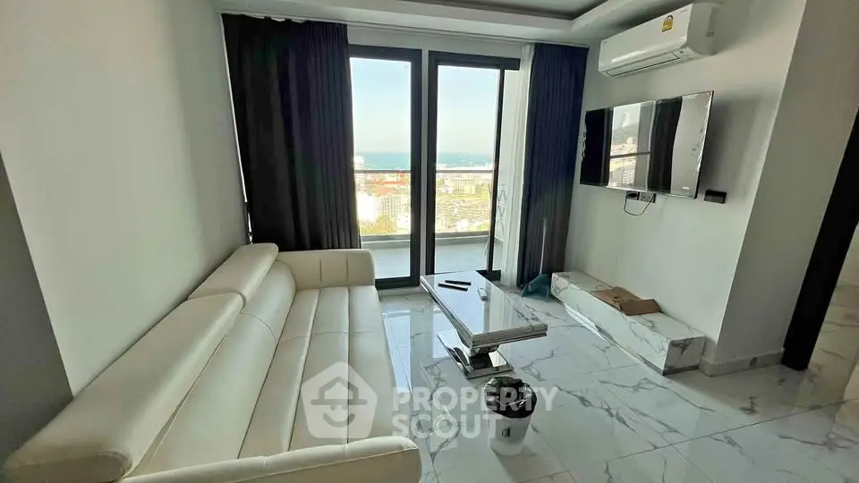 Modern living room with sea view, sleek white sofa, and wall-mounted TV.