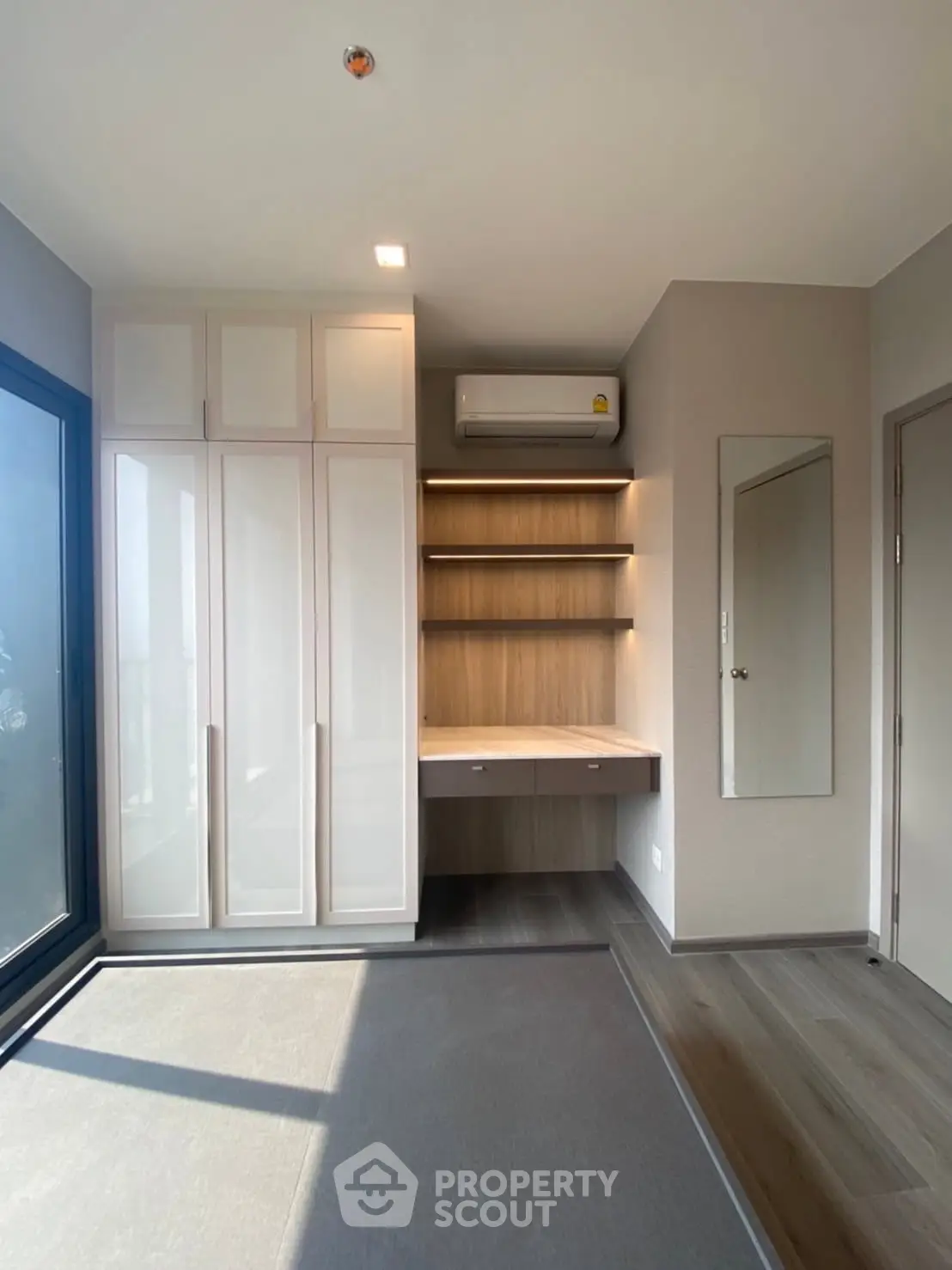 Modern bedroom with built-in wardrobe and study desk, featuring sleek design and ample natural light.