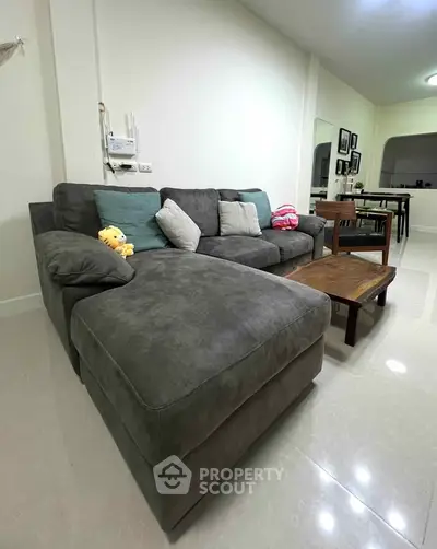 Spacious living room with plush gray sectional sofa and elegant wooden coffee table, perfect for relaxation and entertaining.