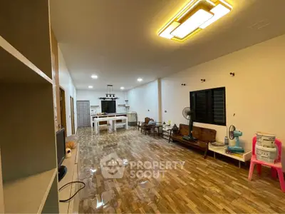 Spacious open-plan living room with modern lighting and wooden flooring, ideal for family gatherings.