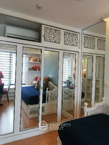 Charming bedroom with mirrored wardrobe and cozy seating area, perfect for relaxation and style.